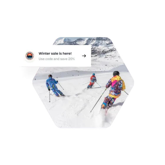 Skiers carving down a piste beside a winter sale card inviting customers to use a code and save 20%