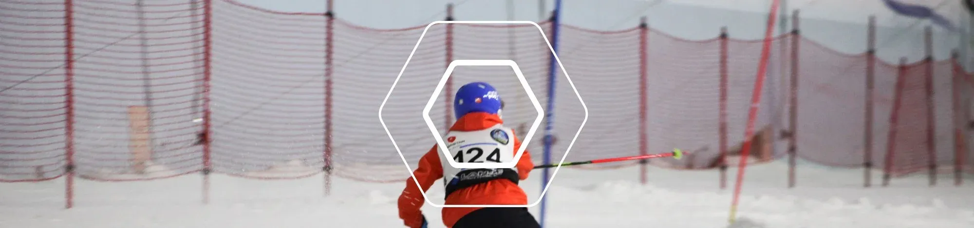 A young ski racer in bib 124 skiing between the gates on an indoor slope
