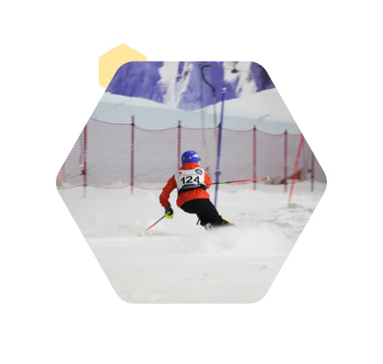 A young ski racer wearing bib 124 carving through a slalom course on an indoor snow slope