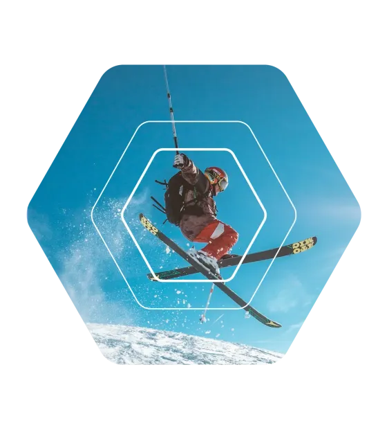 A skier mid-jump against a bright blue sky, framed by eola’s hexagon outlines